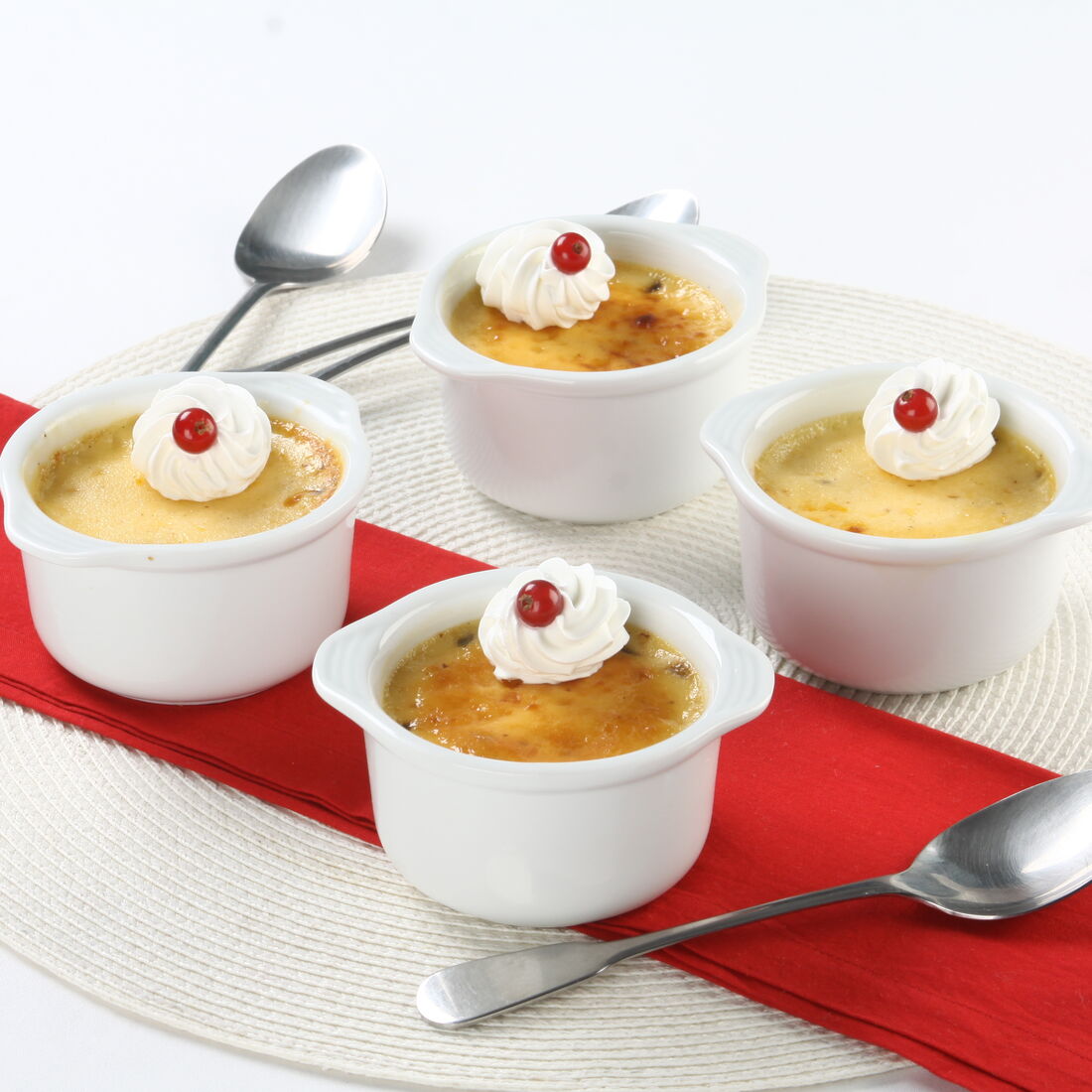 Quatro flãs de baunilha com chantilly e frutos vermelhos em ramequins