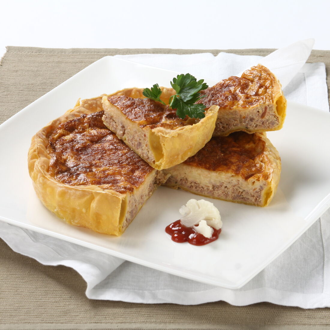 Fatia de tarte bolonhesa servida num prato branco com molho de tomate