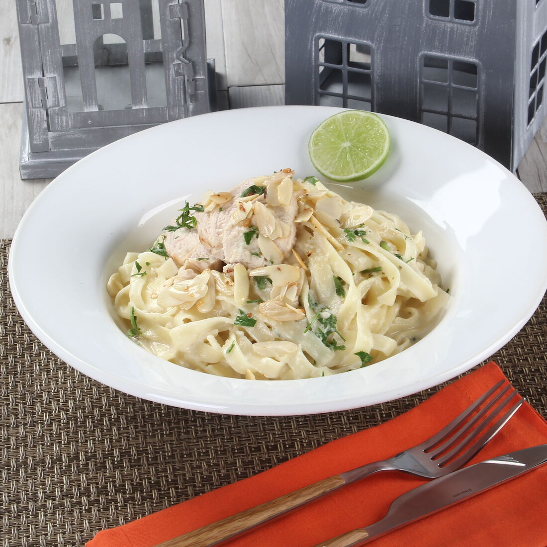 Tagliatelle com creme de frango e amêndoas, guarnecido com salsa e uma rodela de limão