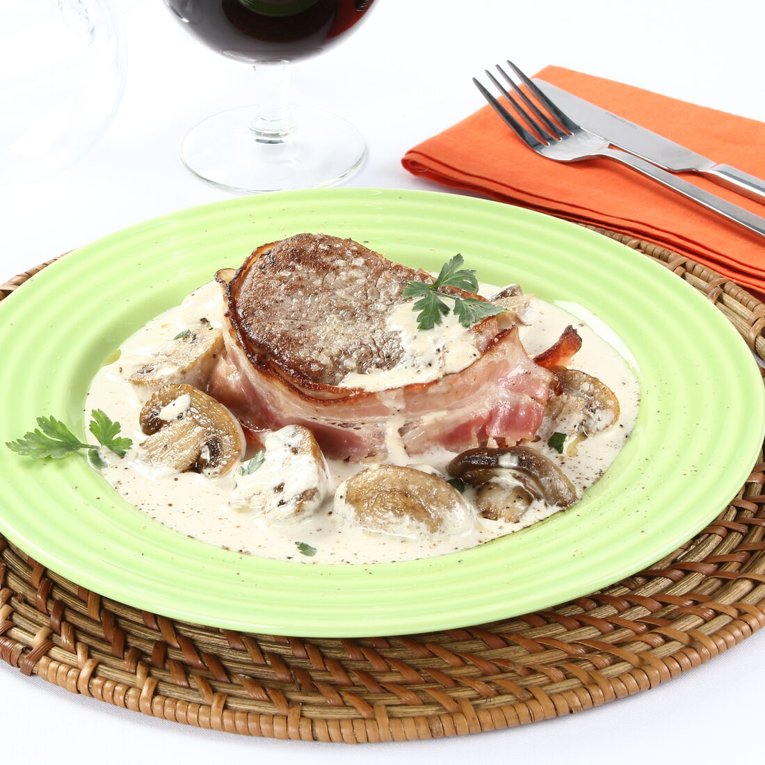 Medalhões de vaca com natas e cogumelos, acompanhados por um copo de vinho tinto