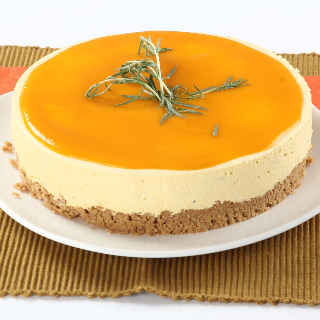 Cheesecake de manga com cobertura de laranja e ramo de alecrim