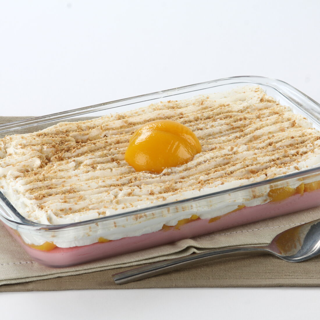 Doce de pêssego em travessa com chantilly e migalhas de bolacha