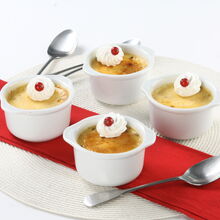 Quatro flãs de baunilha com chantilly e frutos vermelhos em ramequins