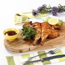 Frango assado servido com limão, salsa e molho numa tábua de madeira