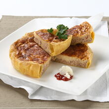 Fatia de tarte bolonhesa servida num prato branco com molho de tomate