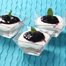 Três copas de cheesecake com molho de frutos vermelhos e hortelã