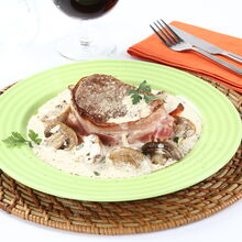 Medalhões de vaca com natas e cogumelos, acompanhados por um copo de vinho tinto