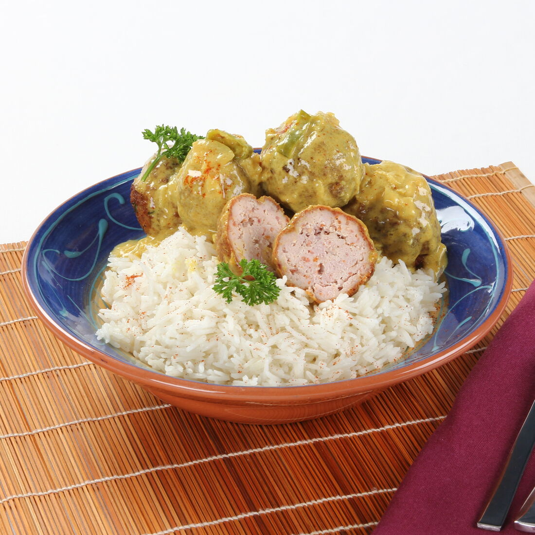 Almôndegas de frango com caril servidas com arroz e guarnecidas com salsa
