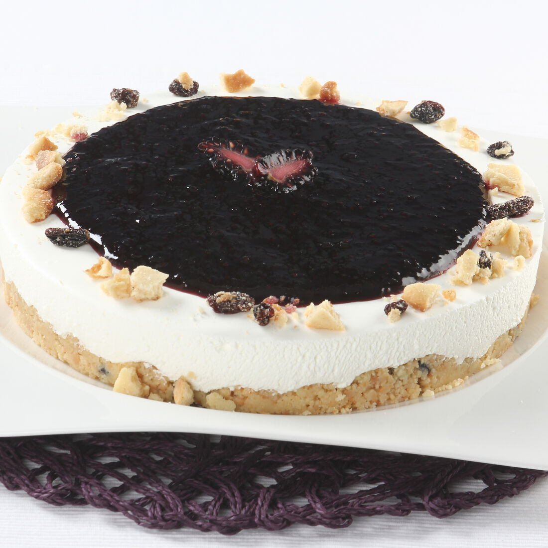 Cheesecake com cobertura de mirtilo, decorado com pedaços de bolacha e frutos secos