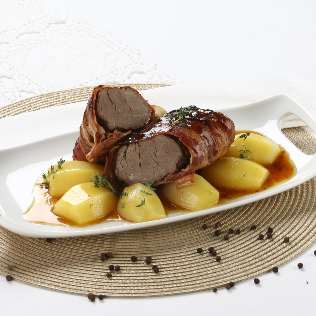 Lombo de novilho com bacon e batatas servido num prato branco