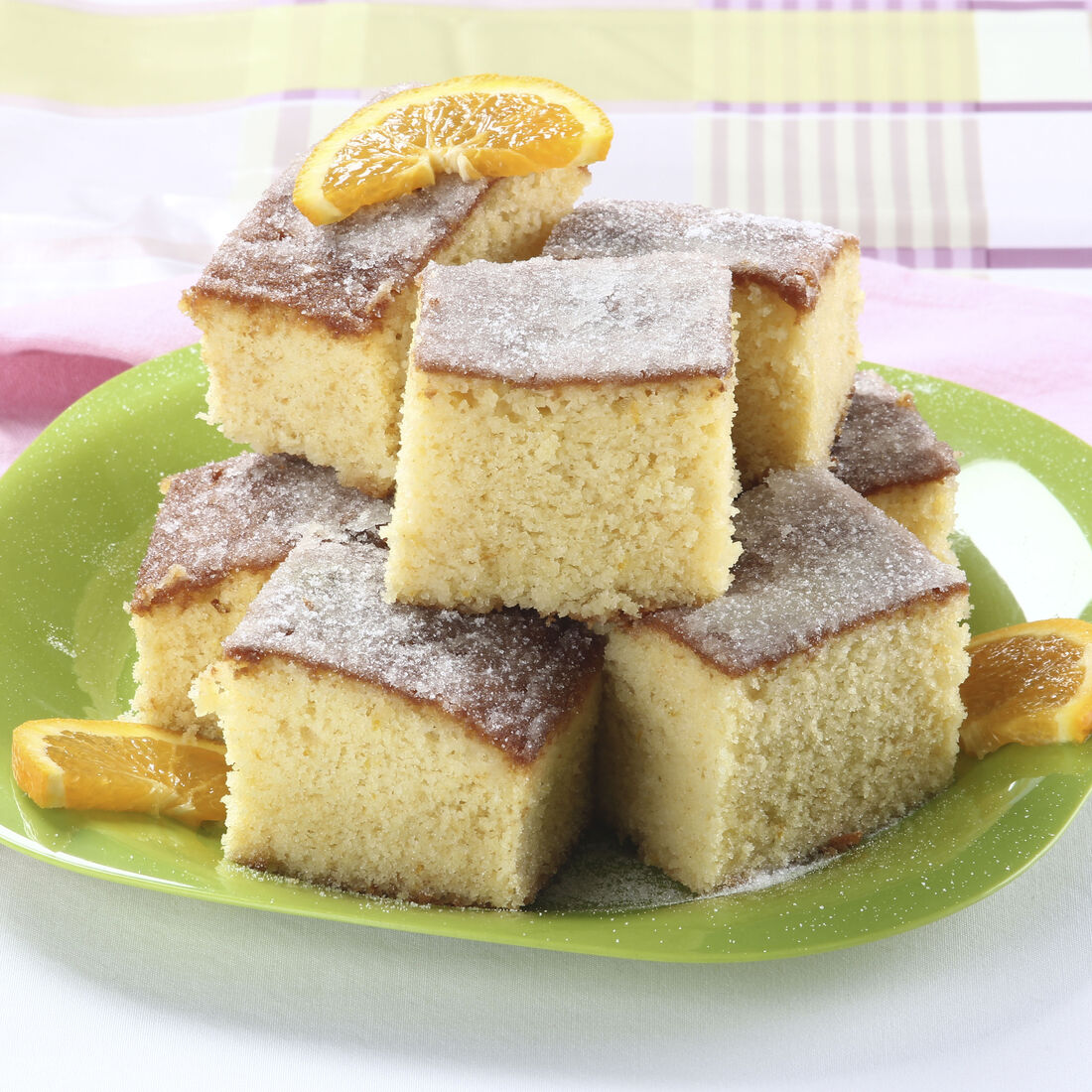 Bolo de laranja com açúcar e rodelas de laranja numa travessa verde