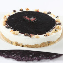 Cheesecake com cobertura de mirtilo, decorado com pedaços de bolacha e frutos secos