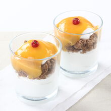 Sobremesas em copo com natas, bolo e fruta, servidas em branco