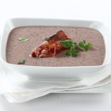 Creme de feijão encarnado com bacon e salsa numa taça branca